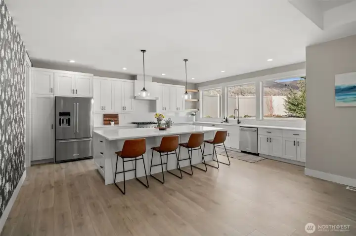 Kitchen features an oversized island, quartz counter tops and gas range.