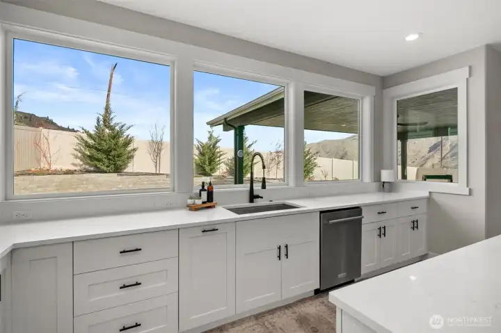 Kitchen sink over looks yard and beautiful mountain and sky view.