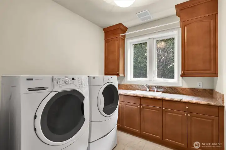 Laundry room with deep sink and cabinets galore.