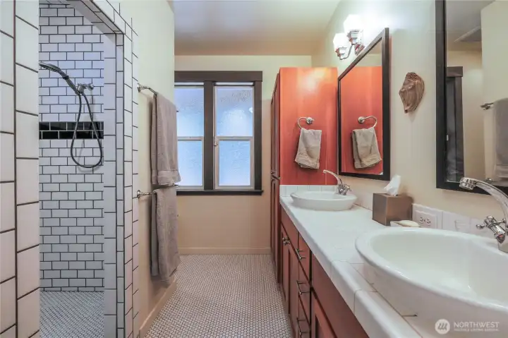 Two sinks and a double shower head full tile shower.