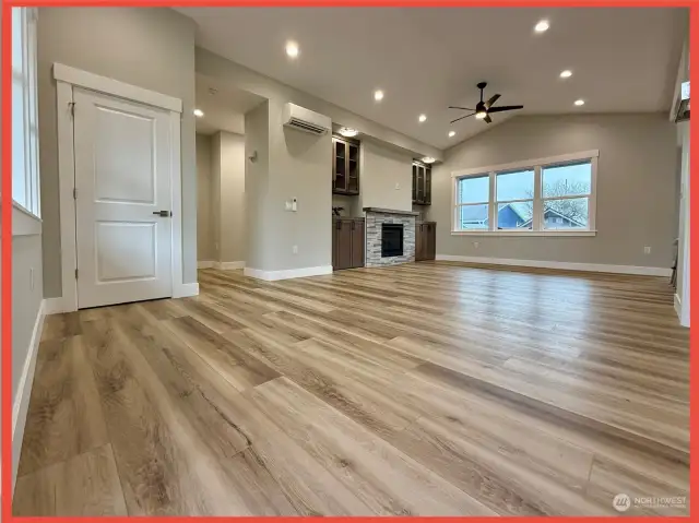 Open concept great room with vaulted ceilings, stack-stone fireplace flanked by built-in cabinets, and luxury vinyl plank flooring. Mini-split AC/Heat.