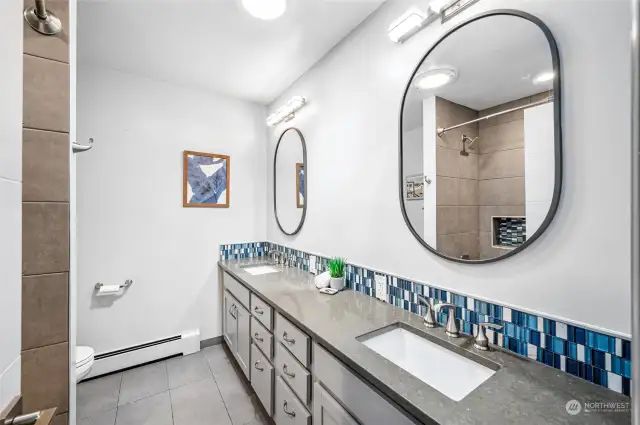The guest bathroom features quartz counters and a tile surround full bath with double sinks and tile floors.