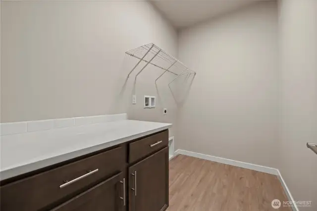 The utility has a cabinet and countertop for folding clothes and extra storage.