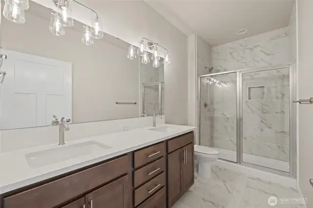 The primary bathroom has two sinks, a tile shower & tile floors.