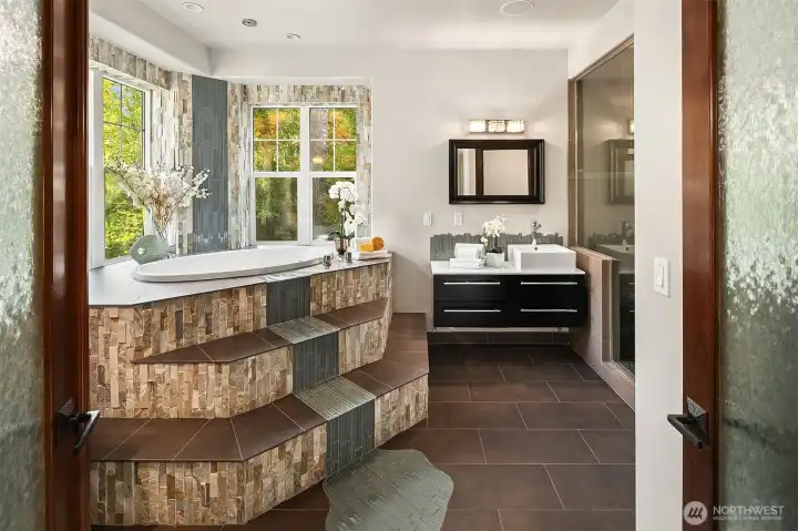 French doors open to the spa like ensuite with custom tile on the jetted soaking tub.  There is a dramatic ceiling mounted waterfall tub filler