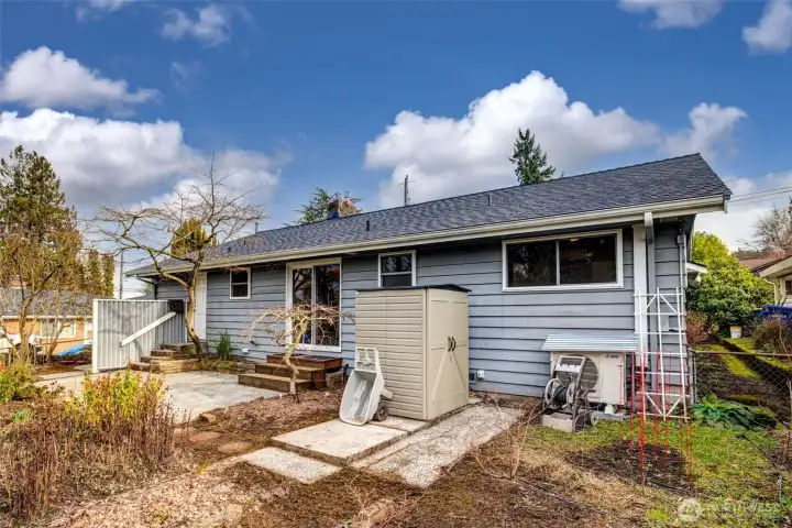 Storage shed and heat pump in fenced backyard.