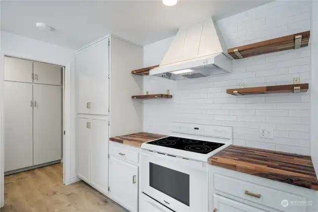 Tile backsplash with extra storage shelving and new fan hood, stove is virtually staged!