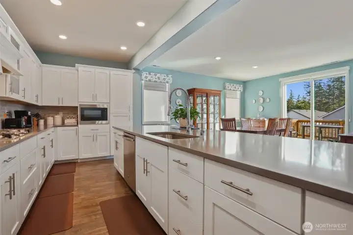 Gourmet kitchen with gas cooktop, double wall oven, french door refrigerator, stainless appliances, slab quartz countertops, center island eating bar that opens to the great room (living and dining rooms).