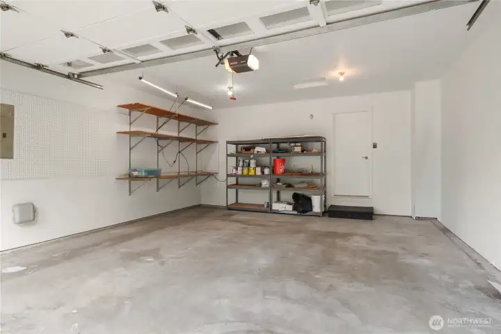 This large 2 car garage has bonus room for shelving and you can see the sprinkler controls to the left. The interior door leads to the laundry room.