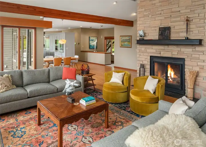 The light-filled living room is anchored by a striking floor-to-ceiling stone fireplace, creating a warm architectural focal point for gathering.