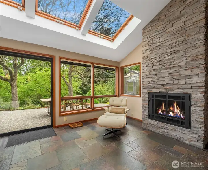 Sunlit fireside retreat off the kitchen opens to a private garden patio for seamless indoor-outdoor living.