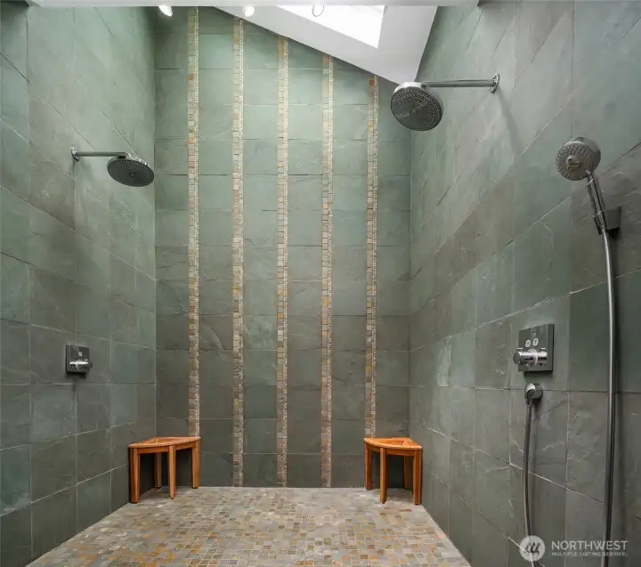 Spa-inspired primary bath with dramatic dual rain shower wrapped in artisan tile and natural light.
