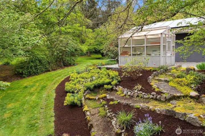 Enchanting greenhouse nestled among curated gardens and lush grounds invites year-round gardening and quiet reflection.