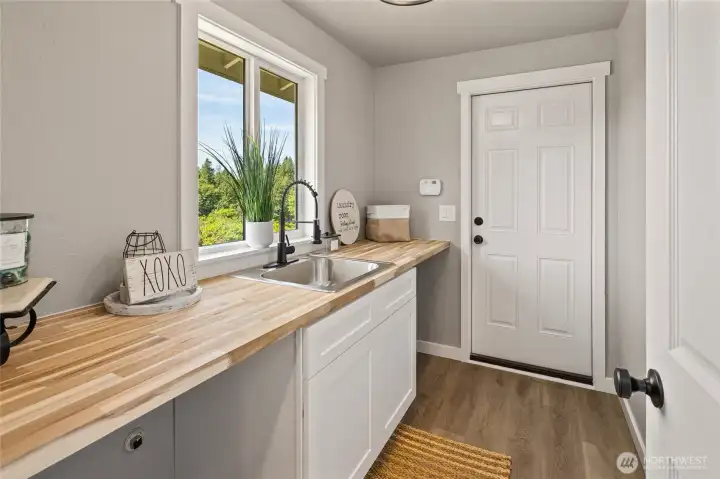 Landry area off of kitchen.  Door leads to deck area and garage! Complete with wash sink, new cabinets and butcher block countertop!