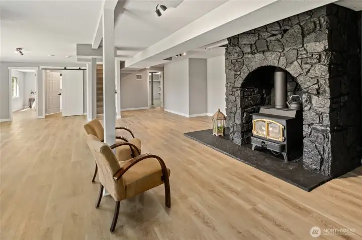 Living room in day light basement complete with rock built with wood fireplace.