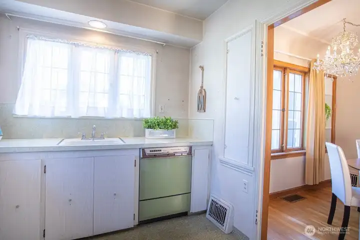 Kitchen adjacent to the dining room with old ironing board cabinet converted to storage