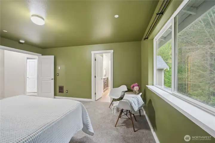 Primary bedroom with large windows looking to the treed backyard