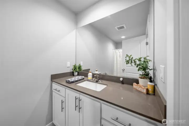 Full bathroom with quartz countertops.