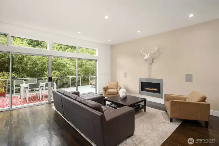 Light-filled living room with expansive windows. The gas fireplace creates a cozy focal point.
