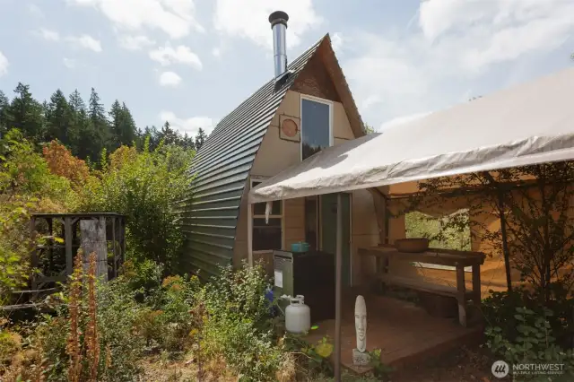 Gothic A Frame dwelling with water, solar array, cooking stove and wood stove.