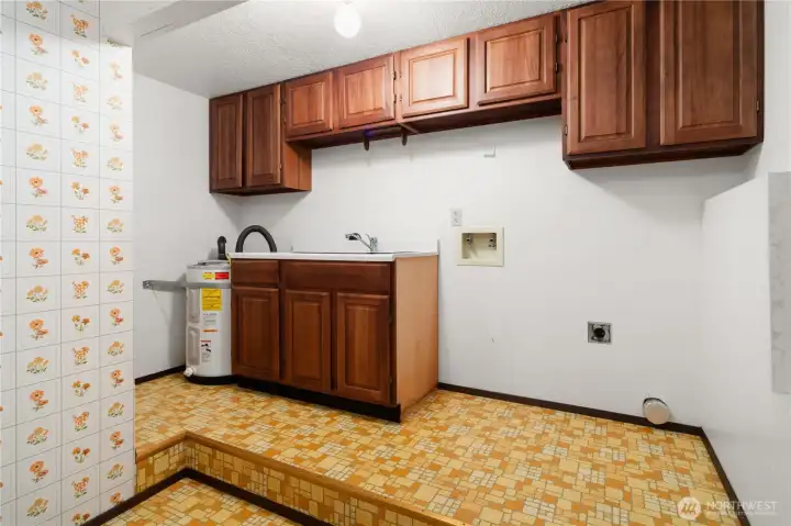 The laundry room can be in the lower level, or in the garage on the main level. This utility room has a deep sink and the hot water heater is on the left.