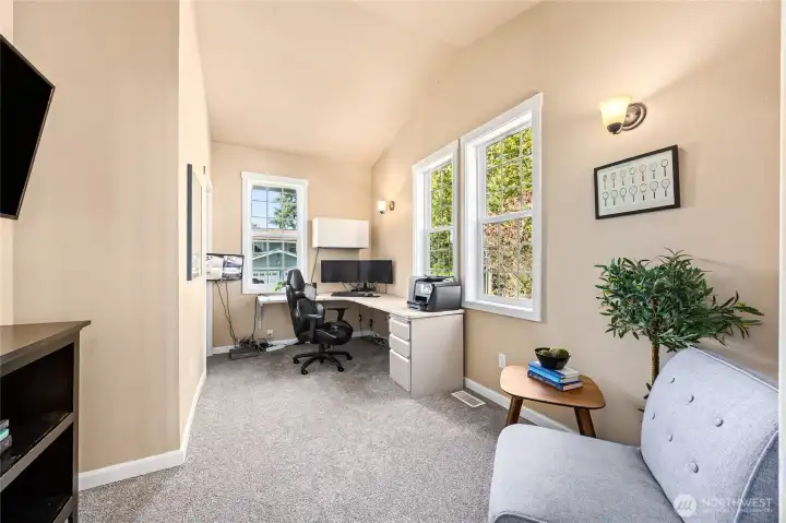 Vaulted main-floor office offers a comfortable workspace; seller plans to leave the desk.