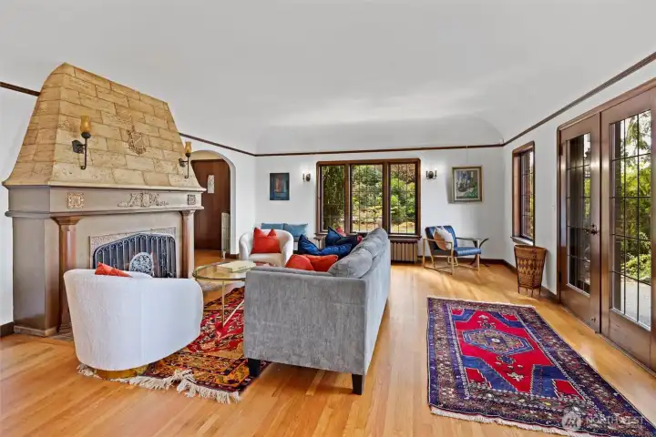 Spacious living room featuring a classic fireplace, abundant natural light, and views through French doors to the sunny back patio and Sound views