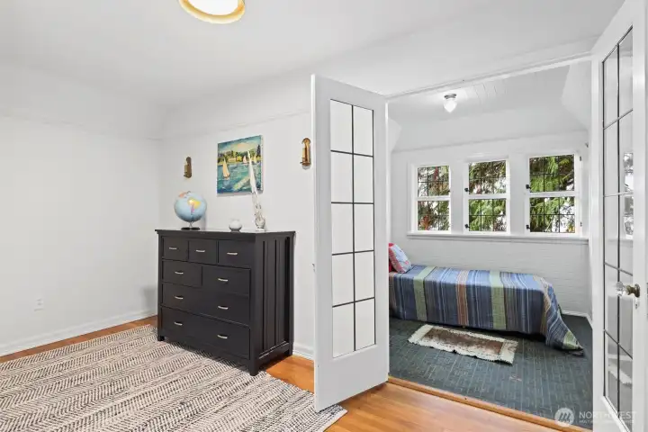 This bedroom features a spacious play area, a cutout with French doors leading to a sleeping nook, and an en suite bathroom for convenience and privacy.