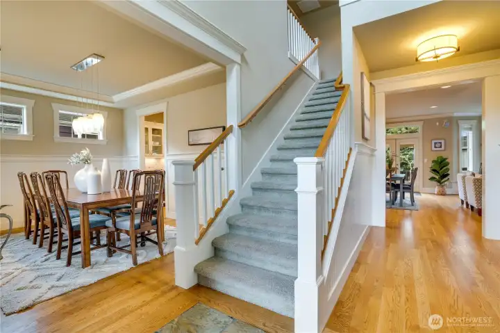 The detailed millwork throughout this home enhances its classic charm despite its modern construction. Notice the tall baseboards, richly layered crown molding, and neatly trimmed transitions into the dining room and great room. The dining room and hallway feature classic beadboard accents along the walls, complemented by a modern plate rail accent.