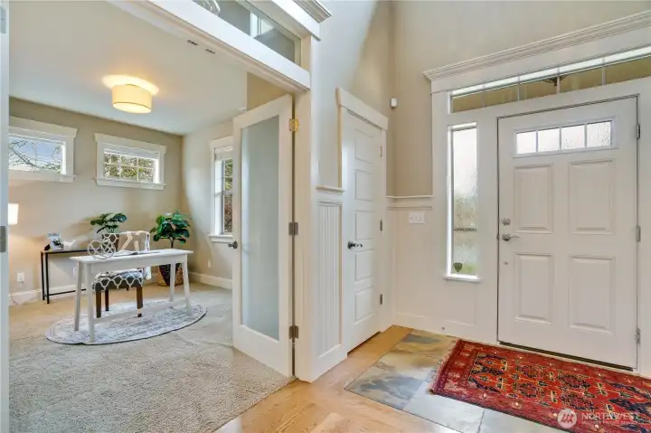 Transom windows above the main floor doors flood the space with natural light. These spaces are complemented by a convenient coat closet, exquisite millwork, a slate entry floor, and soaring ceilings.