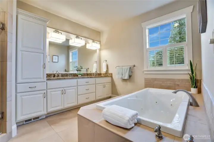 Enjoy a spa-like experience in the primary bath, featuring a jetted tub, ample storage, and a large window that fills the space with natural light. Elegant tile accents and granite countertops add a touch of luxury to this serene retreat.
