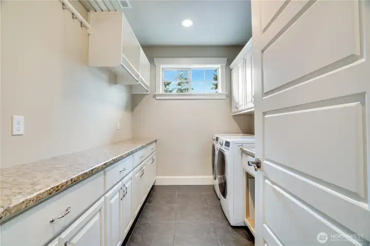 The upstairs laundry room offers plenty of extra storage, handy drying racks, a utility sink, and slate floors that make cleaning a breeze. Right outside, a linen closet keeps towels, sheets, pillows, and blankets neatly organized.