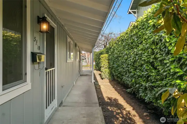 Front entry 5110 along covered breezeway eastern side of the building with mature laurel privacy hedge.