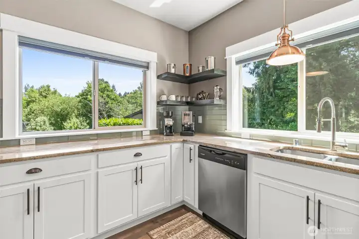 Sleek subway tile backsplash compliments the granite countertops & cabinetry, while large picture windows showcase the backyards privacey.