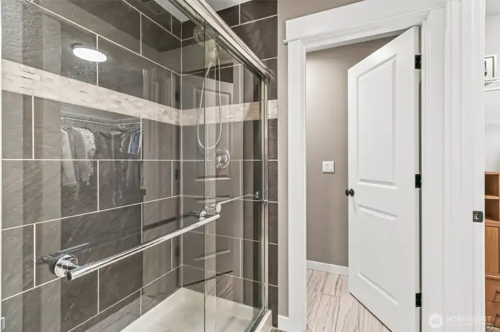 Primary bath features a sleek tile surround with glass doors & decorative tile.