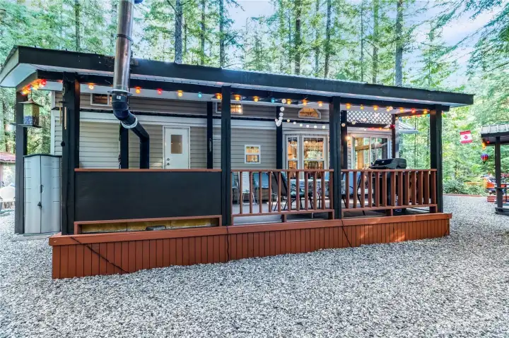 Exterior view of the park model w/ covered deck & pergola lighting.