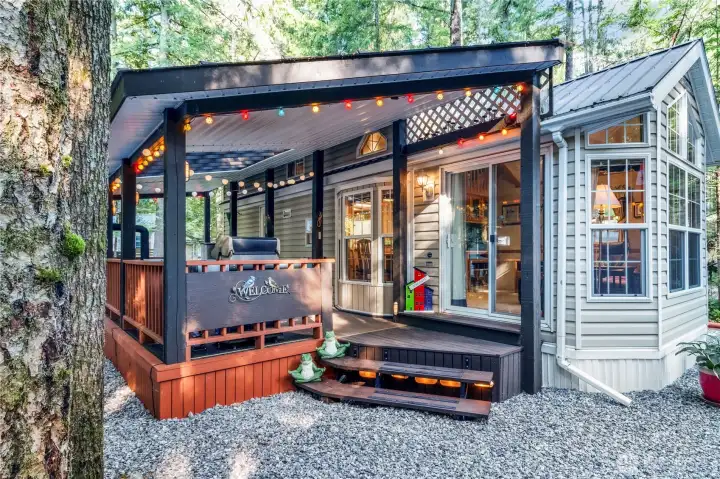 Covered deck entrance w/ warm lighting & seating.