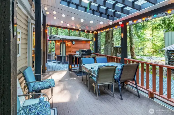 Covered deck dining space under pergola lighting.