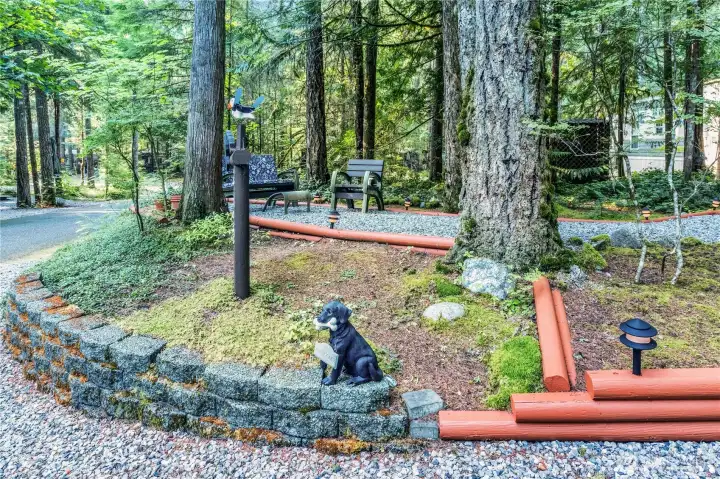Landscaped yard area w/ raised borders & forest setting.