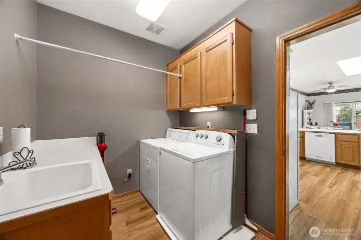 Laundry Room with upgraded flooring & featuring cabinets & utility sink.