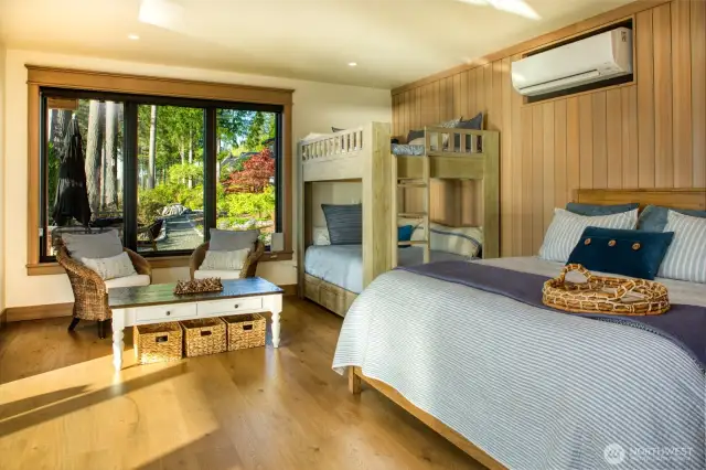 The open space is enveloped in natural light pouring through floor-to-ceiling glass doors, offering a front seat to the serene vista of calm waters and distant shores.