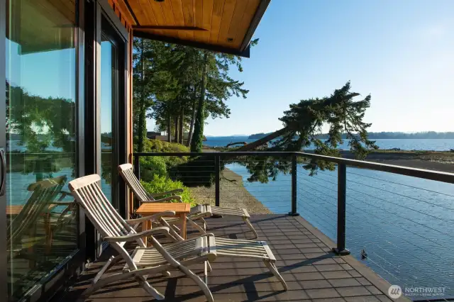The expansive glass doors frame an unobstructed vista of the serene waters, opening onto a deck that seems to float above the landscape. Here, the beauty of the Sound is not just seen but felt, inviting the tranquil essence of the waters into your living space.  The expansive glass doors frame an unobstructed vista of the serene waters, opening onto a deck that seems to float above the landscape. Here, the beauty of the Sound is not just seen but felt, inviting the tranquil essence of the waters into your living space.
