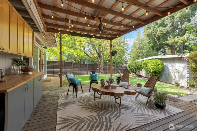 Covered patio off kitchen with built in entertainment storage/bar; overhead fan, and electrical for outdoor lighting.
