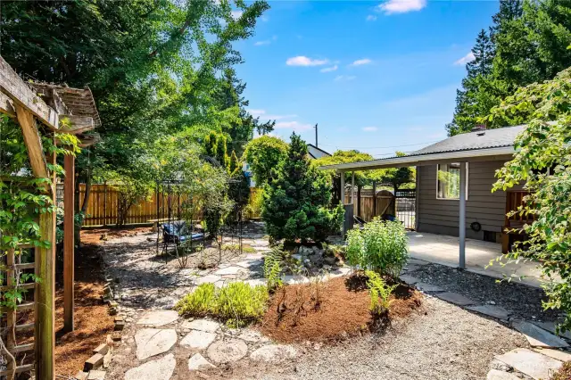 Continuing our tour outside, the backyard is a sweet oasis of entertainment space, mature plantings, and lovely spots to relax.