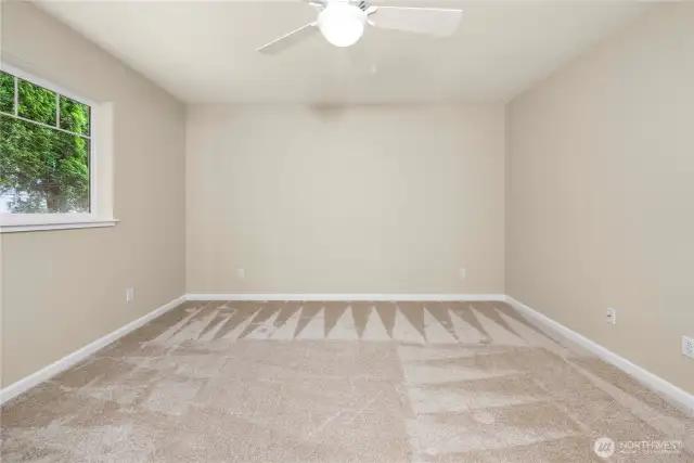 Large, sunlit bedroom with cooling ceiling fan