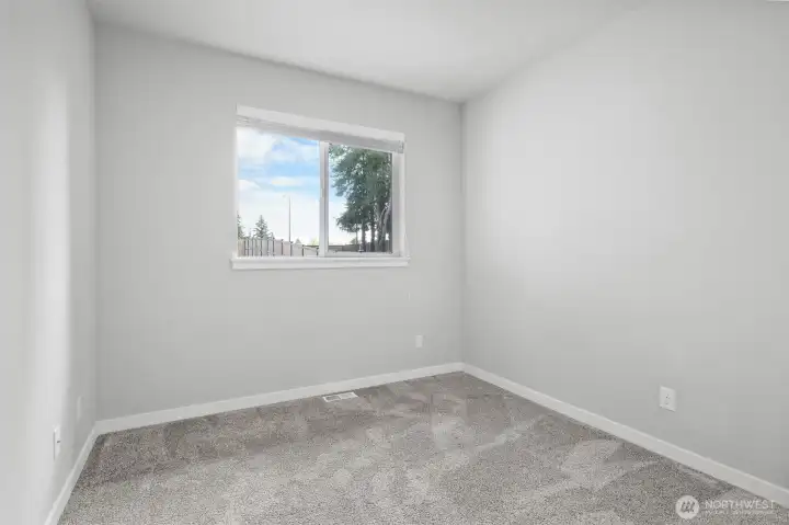 The lower level bedroom has a large window showing beautiful views of the backyard landscape.
