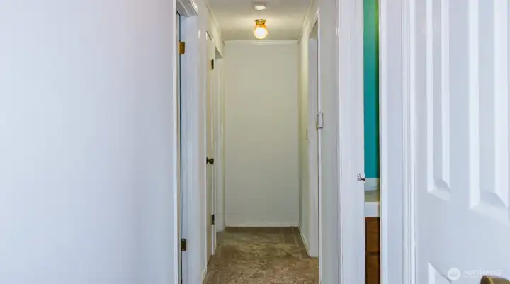 Hallway with 1st door on left as bedroom, 2nd door on left is bonus room that leads to large addition and third bedroom, 1st door on right is full bath with laundry, 2nd door on right is second bedroom.