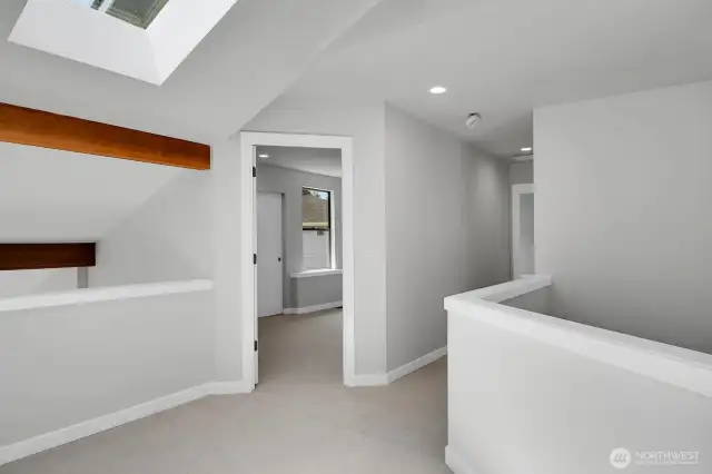 Upstairs landing with skylight and half wall overlooking the living room on the left and the entry on the right.