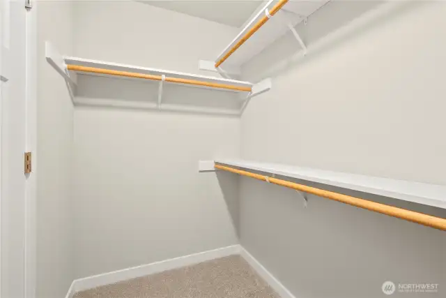 Primary closet is walk-in with extra storage shelves above the hanging rods.