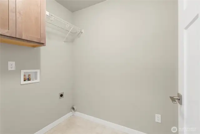 Separate laundry room with a counter, storage cabinets and a storage shelf above appliances.